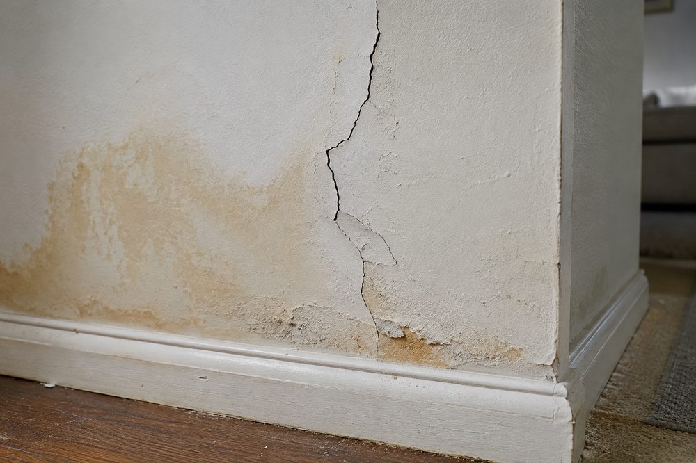 Pared agrietada con mancha de agua, antes de la reparación